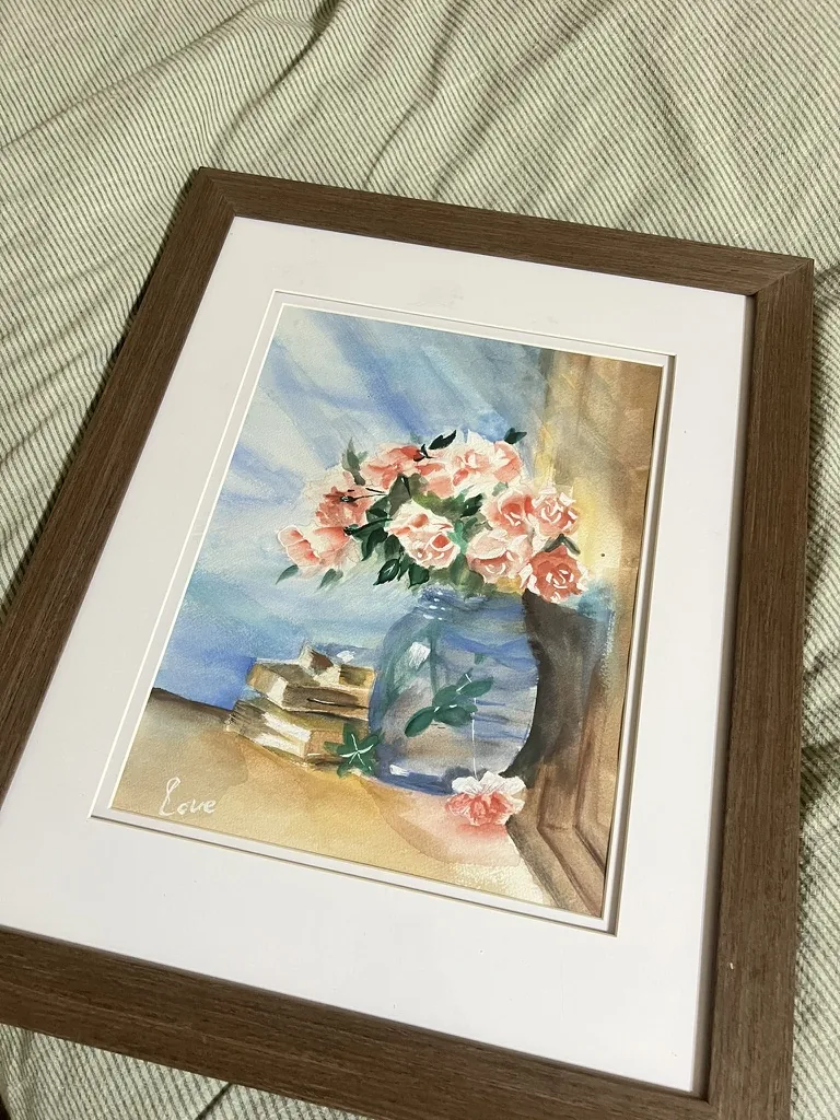 Watercolor still life of pink roses in a glass vase beside books